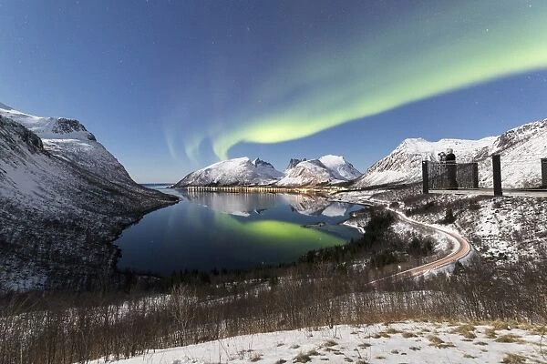 Photographer on platform admires the Northern lights (aurora borealis) and stars
