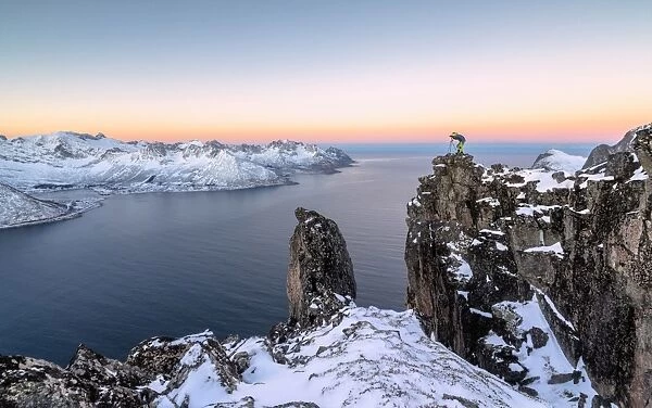 Photographer on the rocks on top of Mount Hesten admires the Mefjorden and the frozen