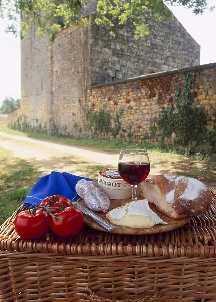 Picnic lunch of bread, cheese, tomatoes and red wine on a hamper in the Dordogne