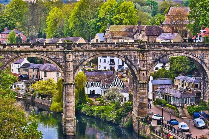 Framed Print : A picturesque view of a stone bridge arching over a river in a quaint village, surrounded by lush greenery and historic buildings Framed Print : A picturesque view of a stone bridge arching over a river in a quaint village, surrounded by lush greenery and historic buildings