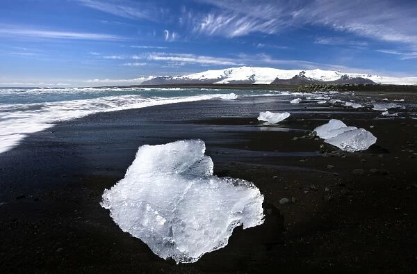 Piece of glacial ice washed ashore by the incoming tide onto beach of volcanic sand near glacial lagoon at Jokulsarlon, Iceland