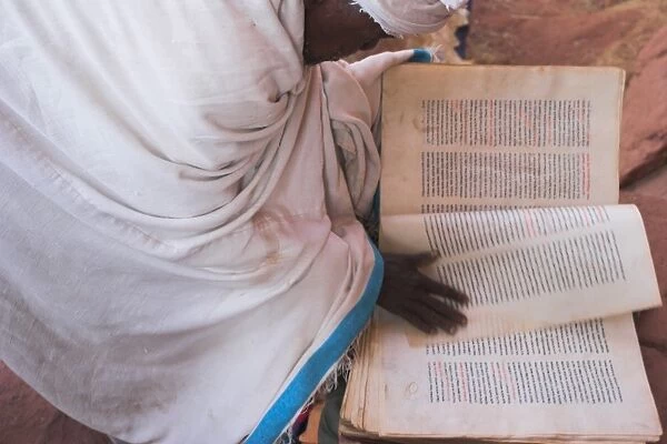 Pilgrim reading religious book on church steps, Lalibela, Ethiopia, Africa