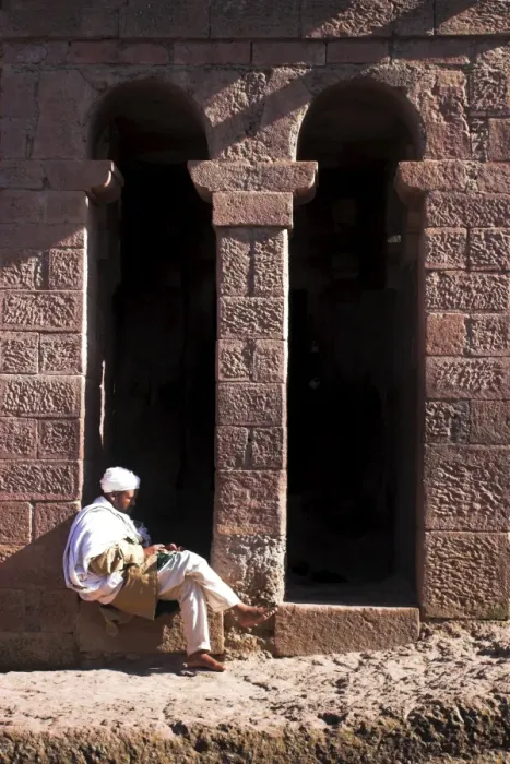 Framed Print : Pilgrim sits in early morning sun reading his Holy Bible at entrance doors to Bet Maryam church Framed Print : Pilgrim sits in early morning sun reading his Holy Bible at entrance doors to Bet Maryam church