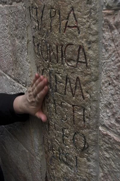 Pilgrims hand caressing the stone at Station VI on