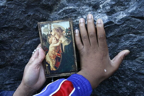 Pilgrims touching the Lourdes grotto, Lourdes, Hautes Pyrenees, France, Europe
