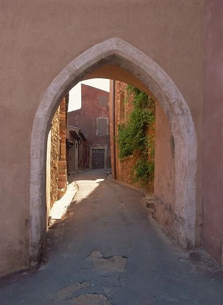 Pink arch over a narrow empty street in the village of Roussillon, Vaucluse
