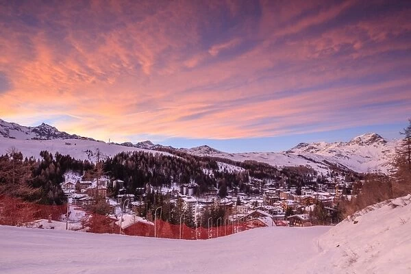 Pink clouds at sunset on the alpine village of Madesimo and the snowy ski slopes