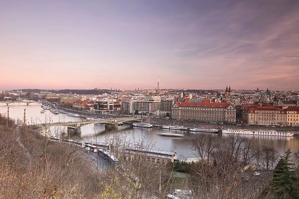 Pink sky on historical bridges and buildings reflected on Vltava River at sunset
