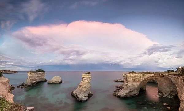 Pink sunset frames the cliffs known as Faraglioni di Sant Andrea and the turquoise sea