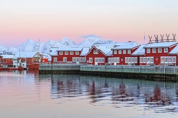 Pink sunset over the typical red houses reflected in the sea, Svolvaer, Lofoten Islands