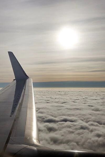Plane wing with low lying clouds and sunburst, United Kingdom, Europe
