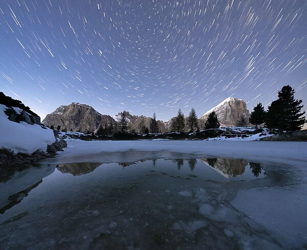 Polar star trail in the night sky over Lagazuoi and Tofana di Rozes peaks from frozen