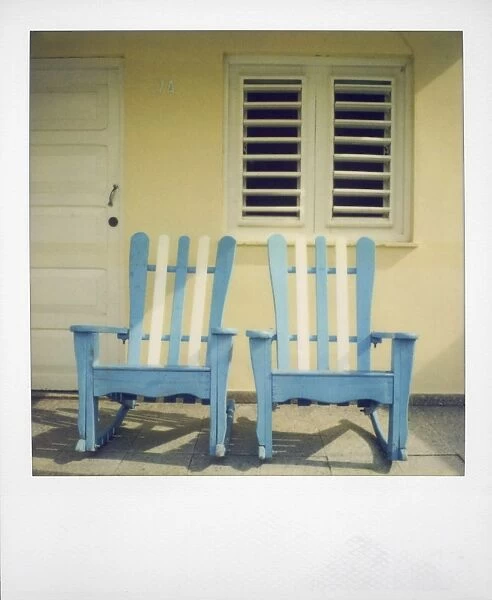 Polaroid of two chairs painted white and blue on porch of traditional house