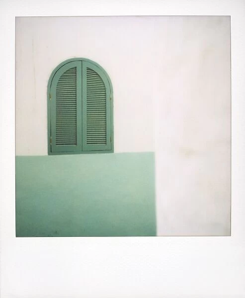 Polaroid of green painted window shutters against whitewashed wall