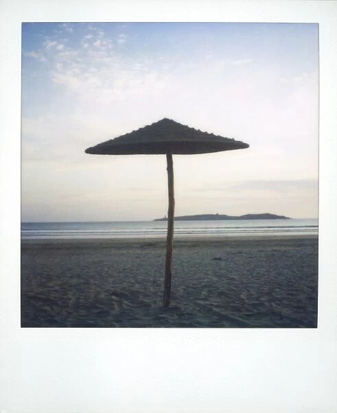 Polaroid image of brach parasol on deserted beach at dusk