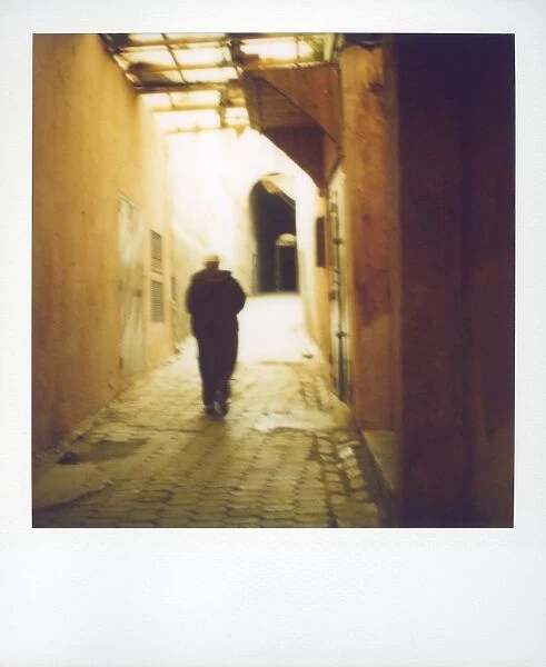 Polaroid image of man walking along narrow
