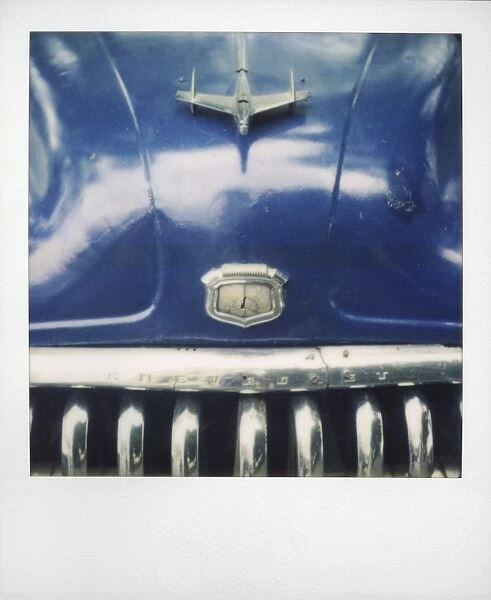 Polaroid of detail of bonnet and chrome grill of blue classic American car