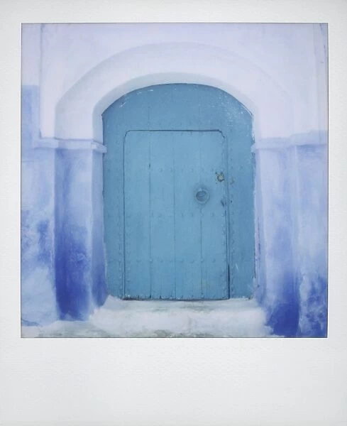 Polaroid of painted blue door against blue and whitewashed wall