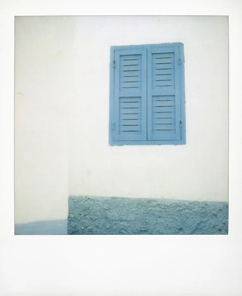 Polaroid of painted blue window shutter against whitewashed wall