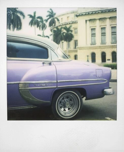 Polaroid of profile of purple classic American car outside the Capitolio