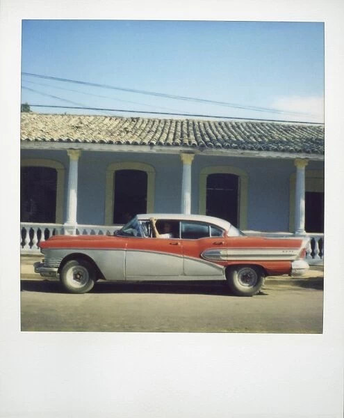 Polaroid of profile of red classic American car parked on street, Vinales