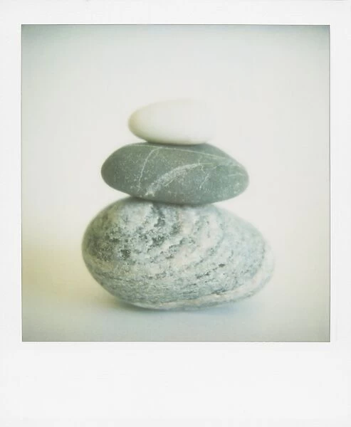 Polaroid of three sea-worn pebbles piled up against a white background