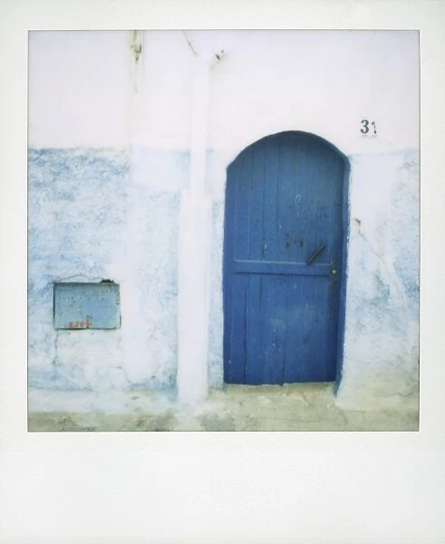 Polaroid of traditional painted blue door against whitewashed wall