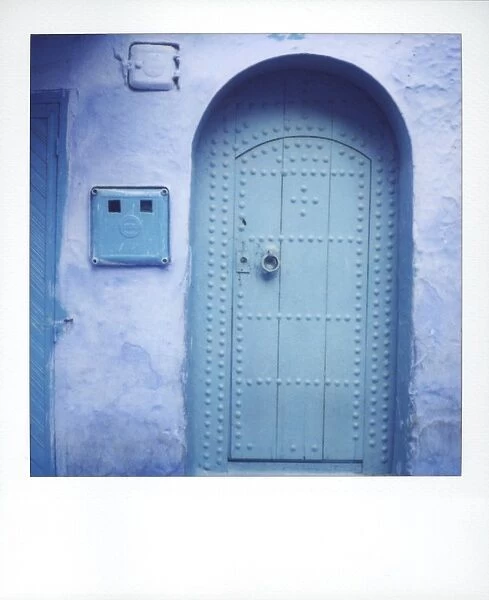 Polaroid of traditional painted blue door against bluewashed wall