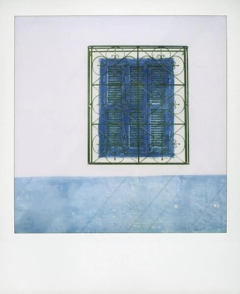 Polaroid of whitewashed wall with blue window shutters