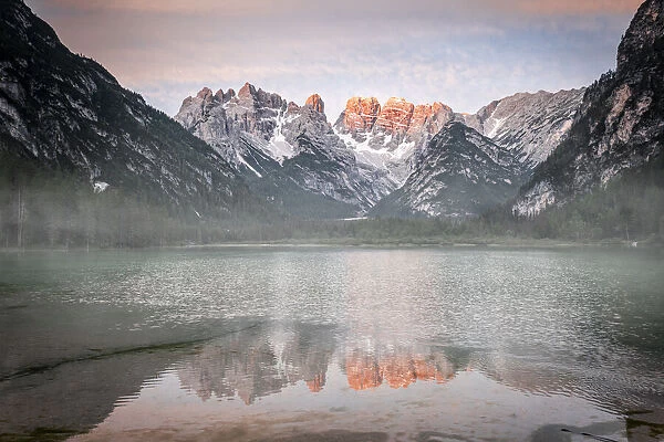 Popena group and Monte Cristallo mirrored in lake Landro (Durrensee) in the mist at dawn