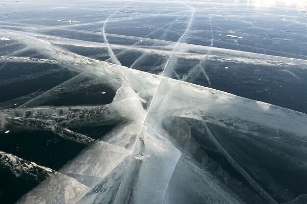 Pressure cracks appear in the 80cm thick clear black ice on the surface of the 800m deep frozen Lake Baikal, Irkutsk Oblast, Siberia, Russia, Eurasia