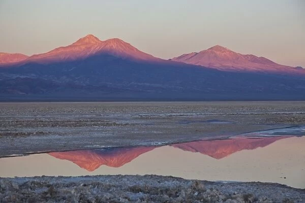 The profiles of two volcanos of the Cordillera de la Sal reflecting in a pool in the Desert of Atacama, Chile, South America