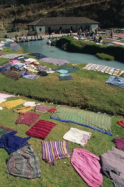 Public washing pool with laundry laid on the ground to dry