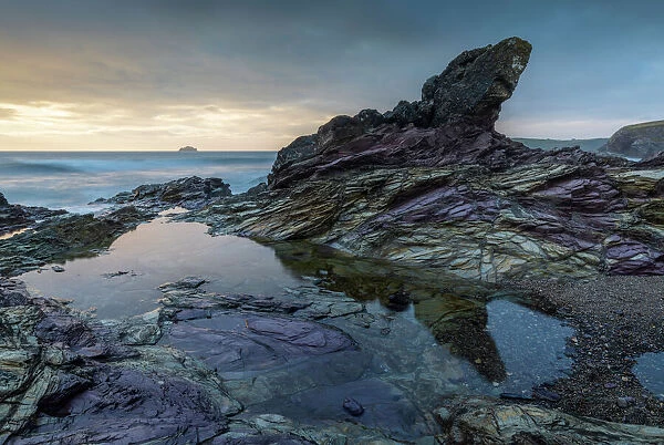 Purple coloured rocks on the Cornish shoreline at sunset, Polzeath, Cornwall, England, United Kingdom, Europe