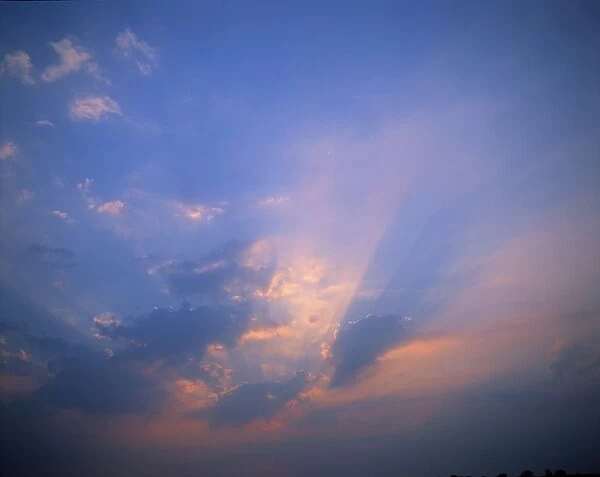 Rays of light bursting through clouds in a blue sky