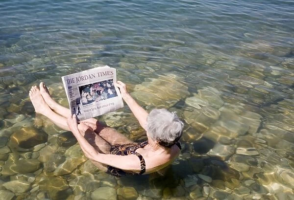 Reading newspaper floating in Dead Sea