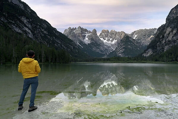 Rear view of hiker man admiring Monte Cristallo reflected in lake Landro (Durrensee