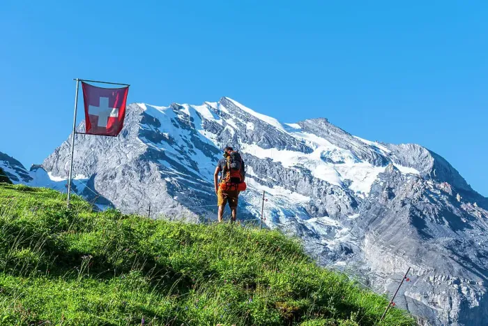 Framed Print : Rear view of a man with backpack hiking the Swiss Alps passing a Swiss flag flying, Oeschinensee, Kandersteg, Bern Canton, Switzerland, Europe Framed Print : Rear view of a man with backpack hiking the Swiss Alps passing a Swiss flag flying, Oeschinensee, Kandersteg, Bern Canton, Switzerland, Europe
