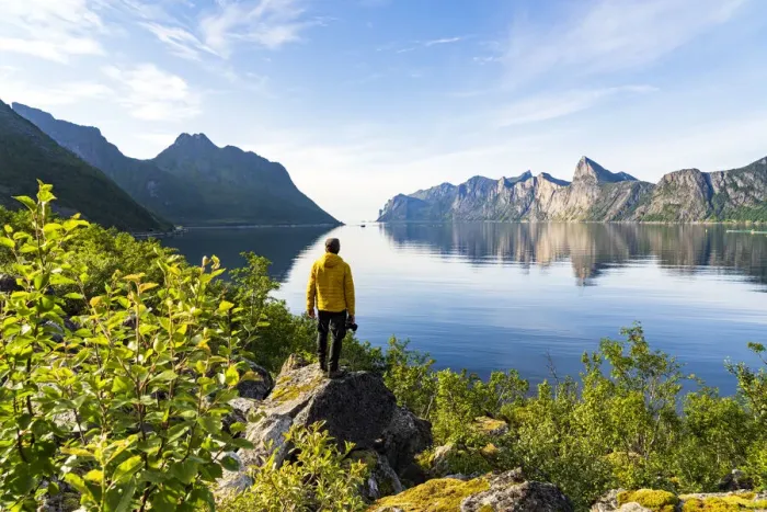 Framed Print : Rear view of photographer admiring the Mefjord blue water standing on rocks, Senja Framed Print : Rear view of photographer admiring the Mefjord blue water standing on rocks, Senja