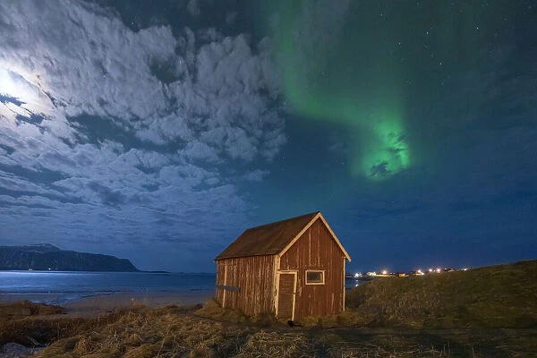 Red cabin under the bright night sky lit by moon and Aurora Borealis (Northern Lights), Ramberg, Nordland county, Lofoten Islands, Norway, Scandinavia, Europe