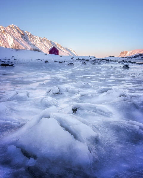 Red rorbuer hut set against a frozen lake, Lofoten Islands, Nordland, Norway, Europe