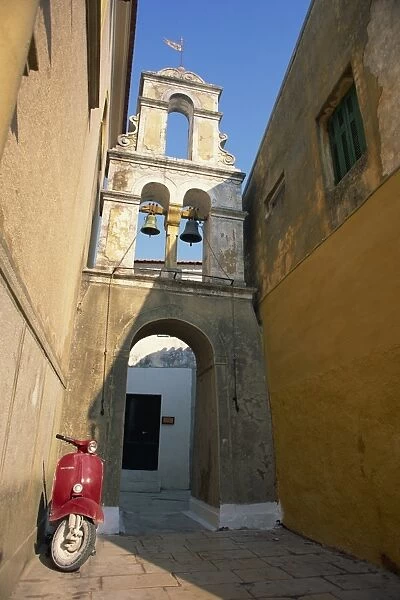 Red scooter parked beneath a bell tower in a back street