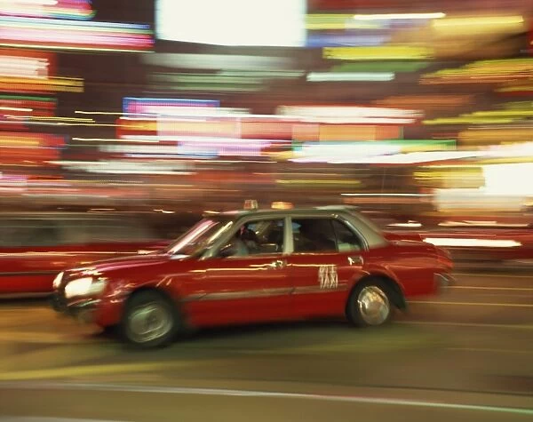 Red taxi driving at speed at night in Causeway Bay, Hong Kong, China, Asia