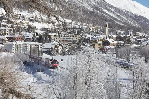 The red train runs across the snowy landscape around Samedan, Maloja, Canton of Graubunden