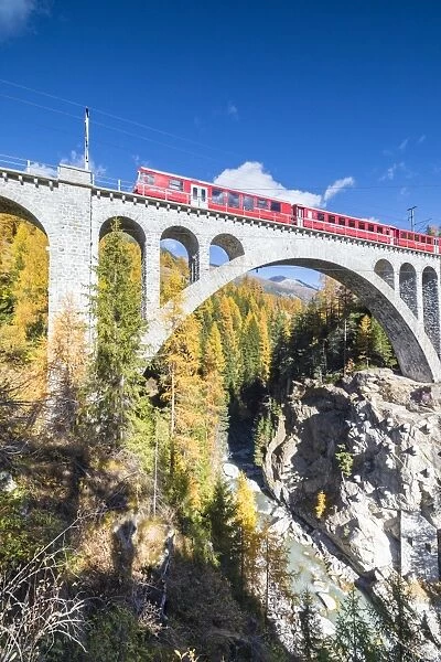 The red train on viaduct surrounded by colorful woods, Cinuos-Chel, Canton of Graubunden