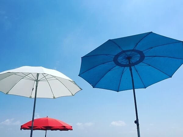 Red, white and blue beach parasols against a blue sky, Nice, Alpes Maritimes, Cote d Azur