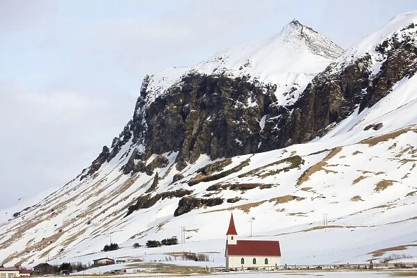 Red and white church against snow covered mountains, Vik, South Iceland, Polar Regions