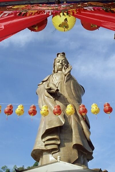 Red and yellow lanterns in front of the standing statue of Kuan Yim