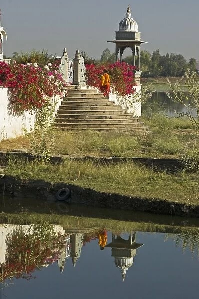 Reflection of monk entering the lake temple for puja at dawn, Dungarpur