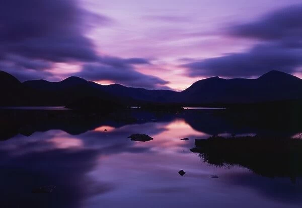 Reflections in the lake of sunset over dark hills of Rannoch Moor in the Highland region of Scotland, United